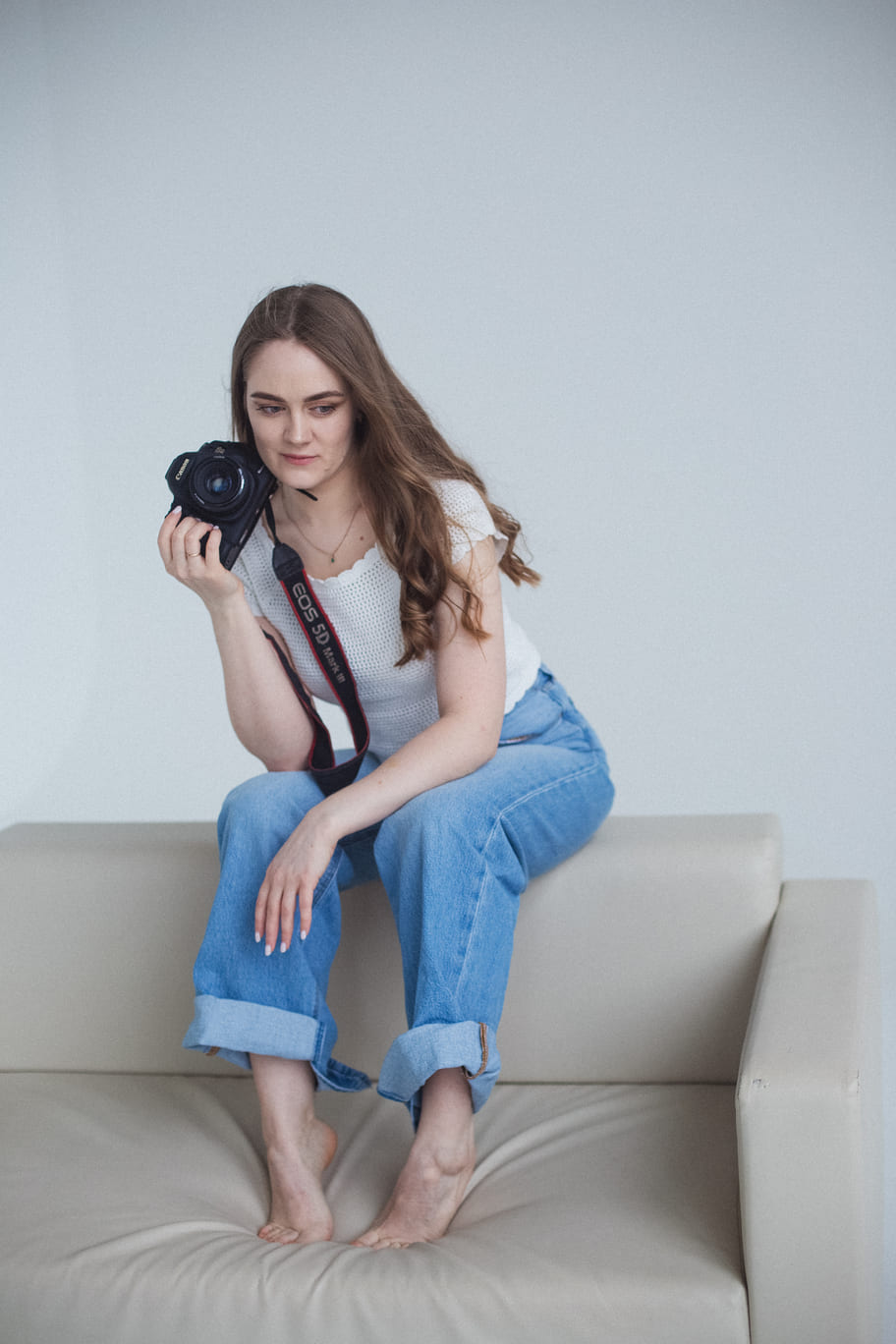 Алина Толмачева с фотоаппаратом сидит на подлокотнике дивана