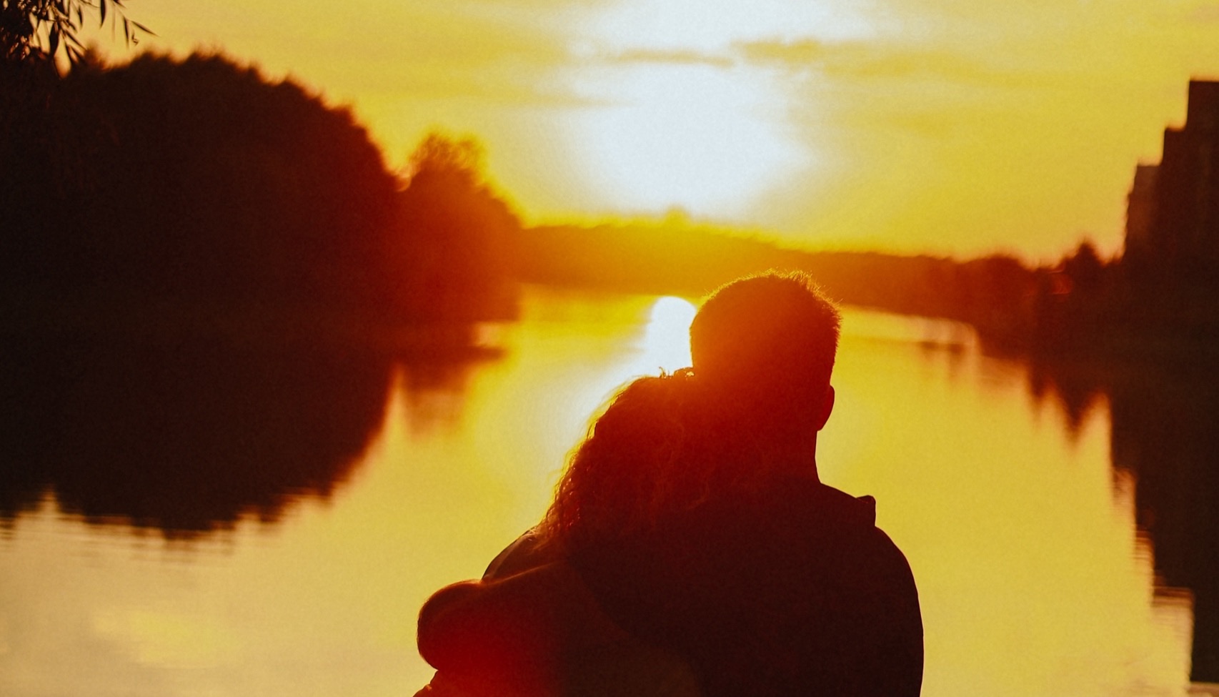 Пара обнимается на скамейке у реки на закате — записаться на love story в Новосибирске